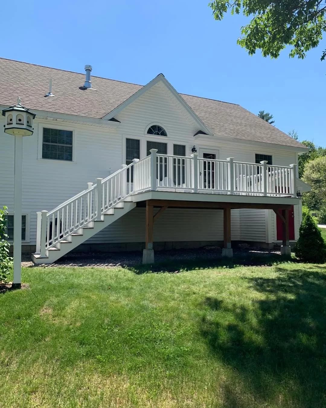 Raised deck with white railing on a large white home — Decks project in Southern NH by A&E Home Improvement