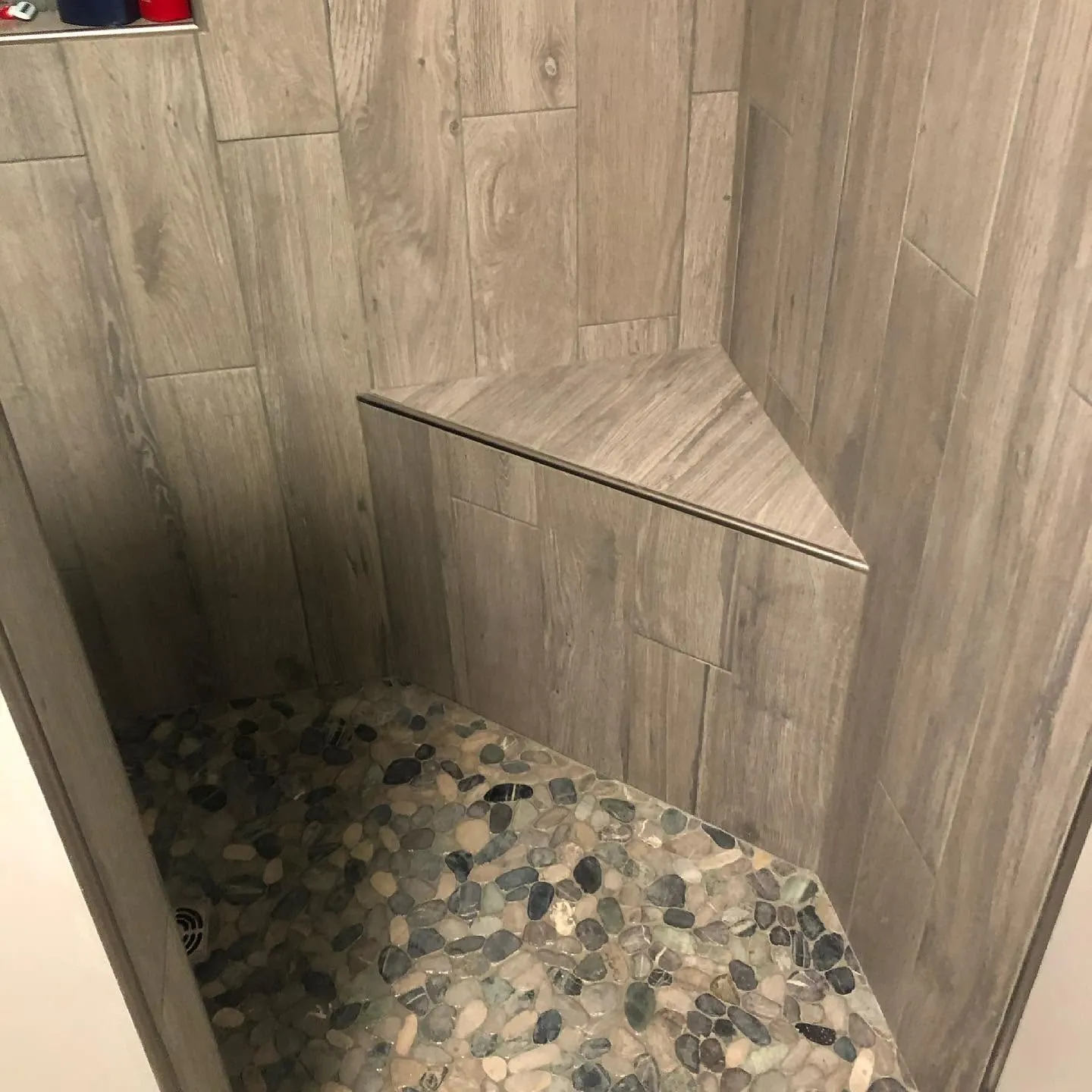 Tiled shower with bench and pebble floor — General Contracting project in Central NH by A&E Home Improvement