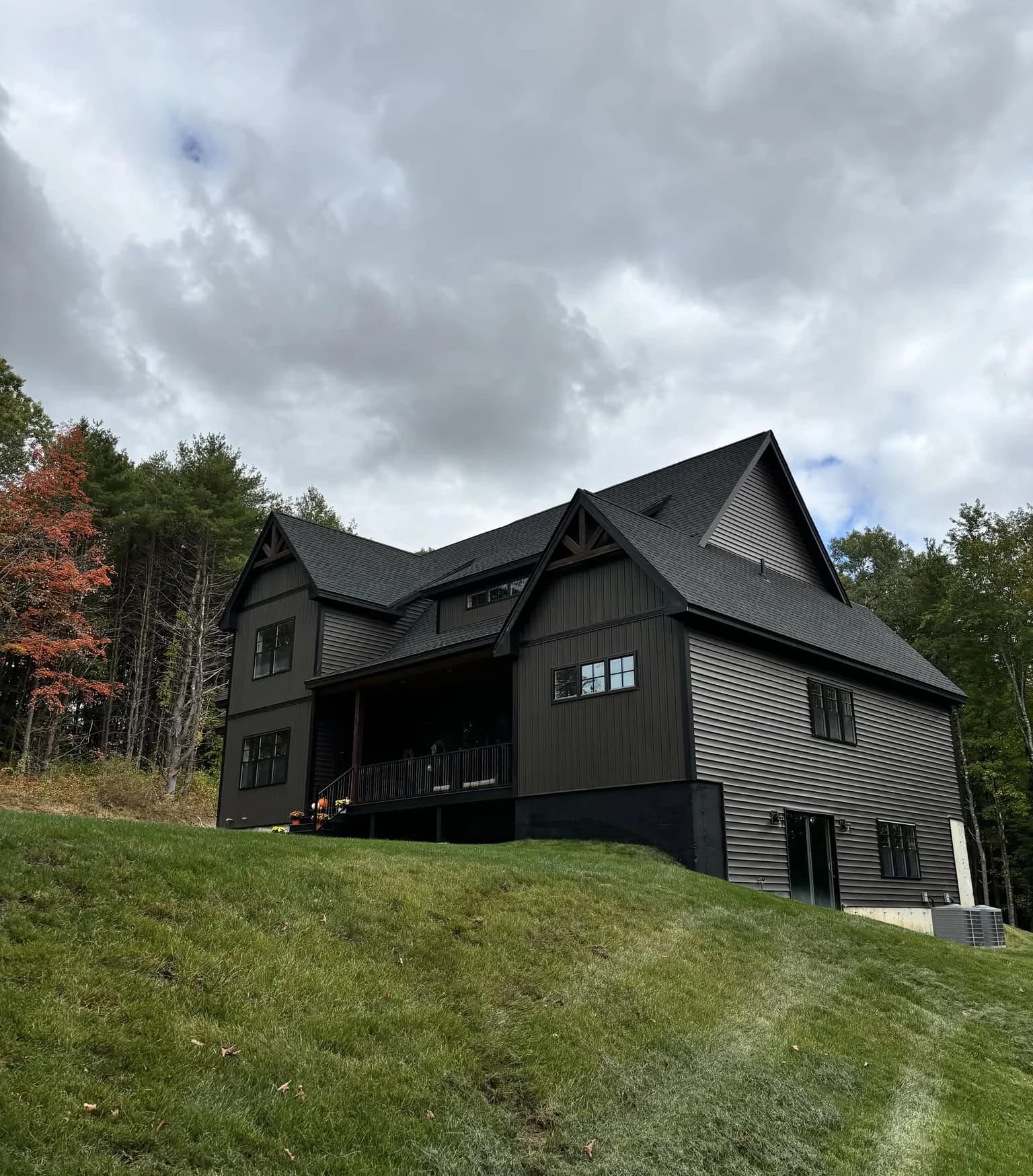 Black board-and-batten farmhouse with a covered porch, built by A&E in New Hampshire