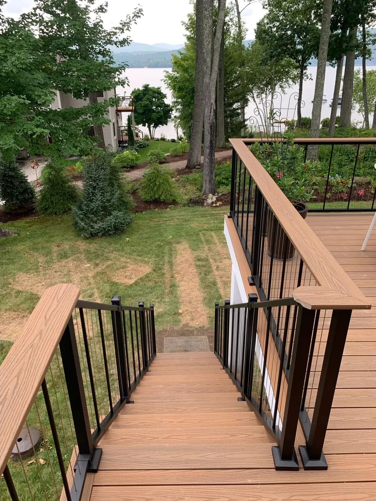 Deck stairs with black metal railing and a lake view — Decks project in Lakes Region, NH by A&E Home Improvement