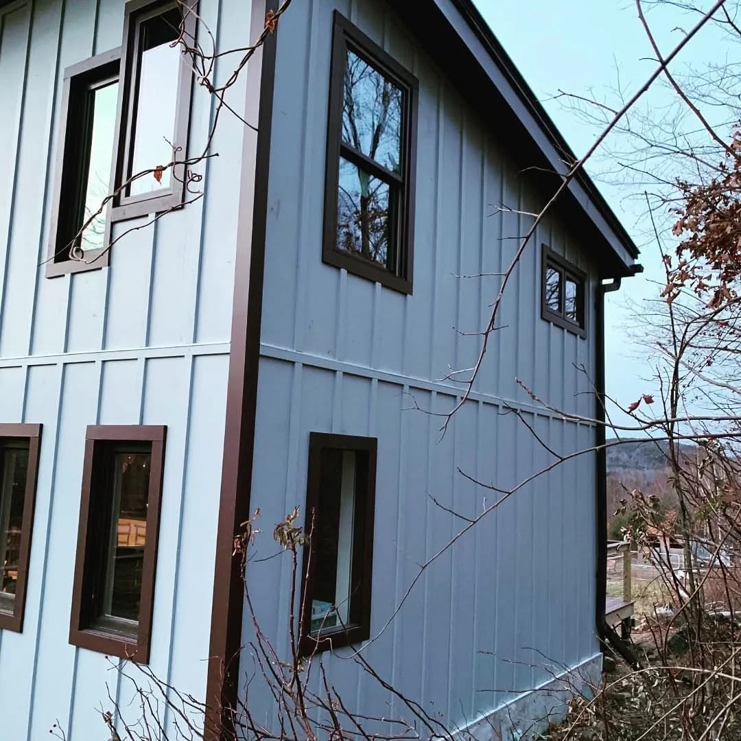 Vertical board-and-batten siding with dark window trim — Siding project in Lakes Region, NH by A&E Home Improvement